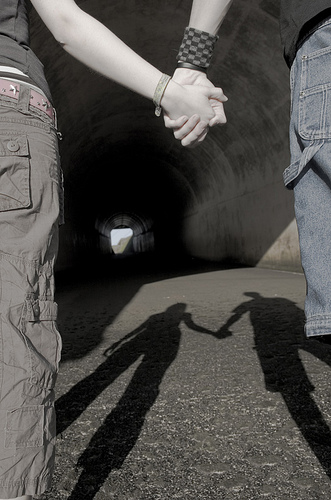 Two people holding hands at the mouth of a tunnel. Uploaded by Adam Foster on flickr