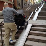 Man pushes stroller up tracks covering stairs in Stockholm