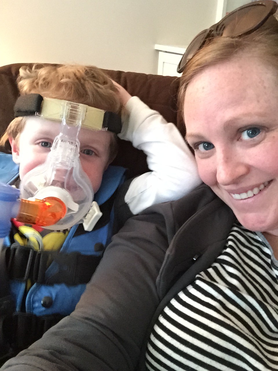 Boy wearing nebulizer mask and his mom