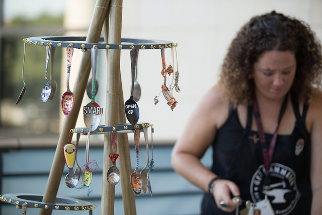 A woman stands near a display of spoons that have been painted