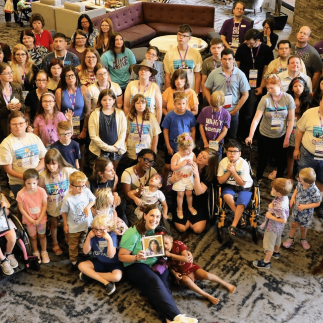 A large group of people of all ages looking up at a camera